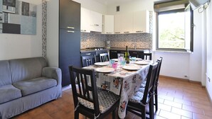 Eine moderne Küche mit gefliestem Fliesenspiegel, einem Esstisch gedeckt mit Tellern und Gläsern, und einem grauen Sofa im Wohnbereich.
