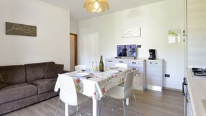 A modern kitchen with a dining area, a sofa, and a TV.