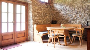 Une pièce rustique avec un mur en pierre, des meubles en bois et une grande porte en bois.