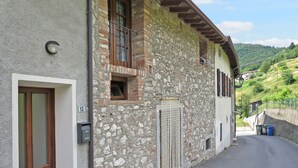 Un bâtiment en pierre avec une porte et une fenêtre en bois, un mur en pierre et une route pavée.
