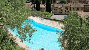 Una piscina rodeada de vegetación, con edificios y una vista distante de colinas y agua.