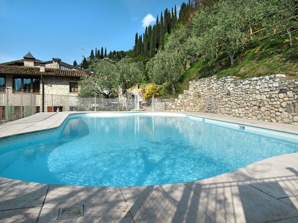 A swimming pool with a stone wall and trees in the background.