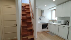 A modern kitchen with white cabinets, a wooden staircase, and a built-in oven.