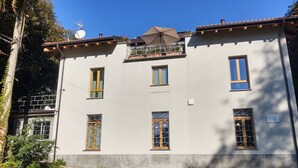 A two-story building with multiple windows, a balcony, and a satellite dish. - Federico by Interhome (Dorio)