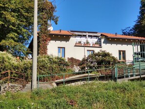 Um edifício de dois andares com telhado de telhas, varanda e antena parabólica.