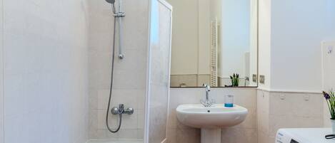 A bathroom with a bathtub, a sink, a mirror, and a washing machine.