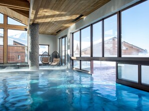 Piscina interior con vistas despejadas a montañas nevadas a través de grandes ventanales.