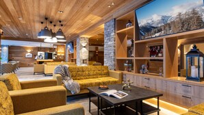 A modern interior with wooden ceilings, a stone accent wall, and a large window with a mountain view. - CGH Rés&Spa White Pearl 5* by Interhome (La Plagne)