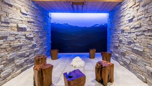 A stone-walled room with a wooden ceiling, a large window, and four wooden stools. - CGH Rés&Spa White Pearl 5* by Interhome (La Plagne)