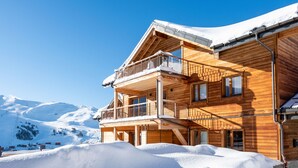A wooden chalet with a balcony, surrounded by snow and mountains. - CGH Rés&Spa White Pearl 5* by Interhome (La Plagne)