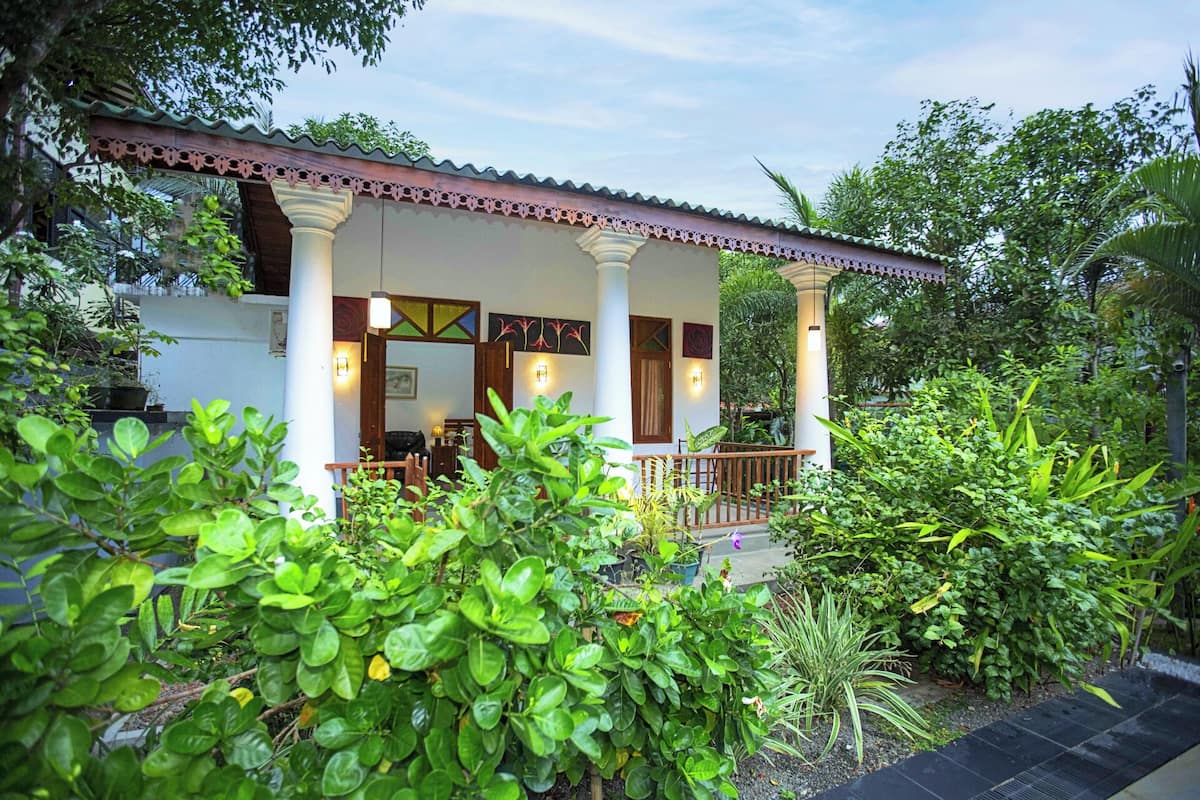 A house with a porch, surrounded by lush greenery.