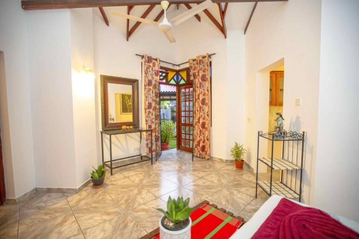 A spacious hallway with a tiled floor, a ceiling fan, and a door leading to a conservatory.
