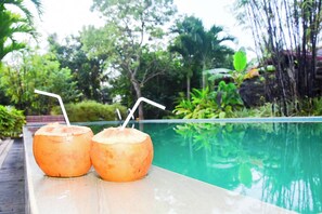Two coconuts with straws on a wooden ledge by a pool. - Arcadia Resort (Hikkaduwa)