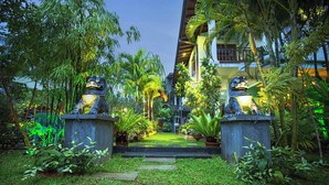 Un sendero de jardín que conduce a un edificio con dos estatuas de leones en la entrada.