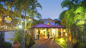 Entrada a un resort con un porche cubierto, palmeras y un letrero que dice 'Arcadia Resorts'.