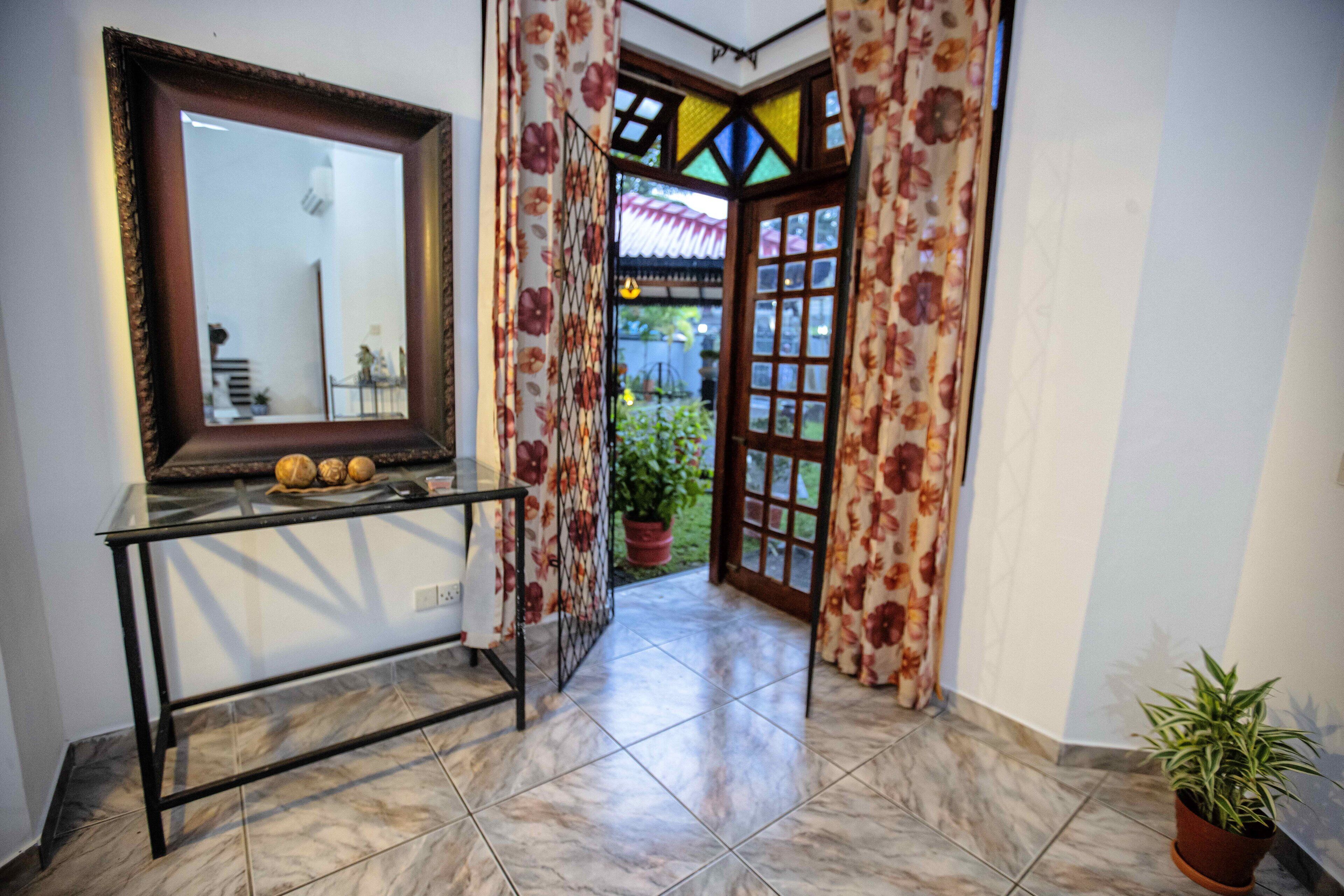 Un pasillo con una mesa de vidrio, un espejo y una puerta que da a un jardín.