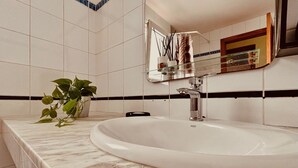 Un baño con un lavamanos blanco, un espejo y una planta en maceta.