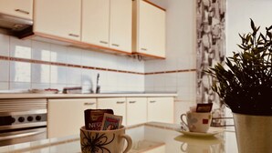 Una cocina con armarios blancos, horno de acero inoxidable y una planta en la encimera.