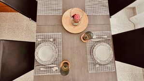 Una mesa de comedor con cuatro puestos, cada uno con un mantel individual estampado, una copa, un plato y un tenedor.