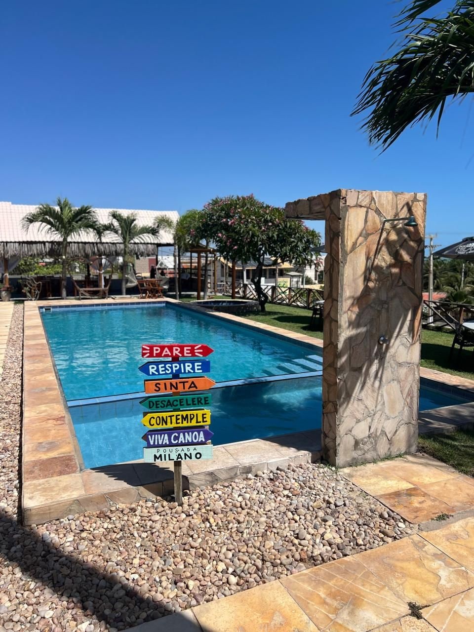 A swimming pool with a stone pillar and a sign with motivational phrases.
