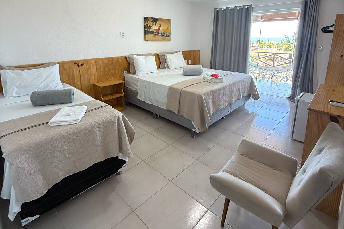 Habitación de hotel con dos camas, una silla, un escritorio y un cuadro en la pared.