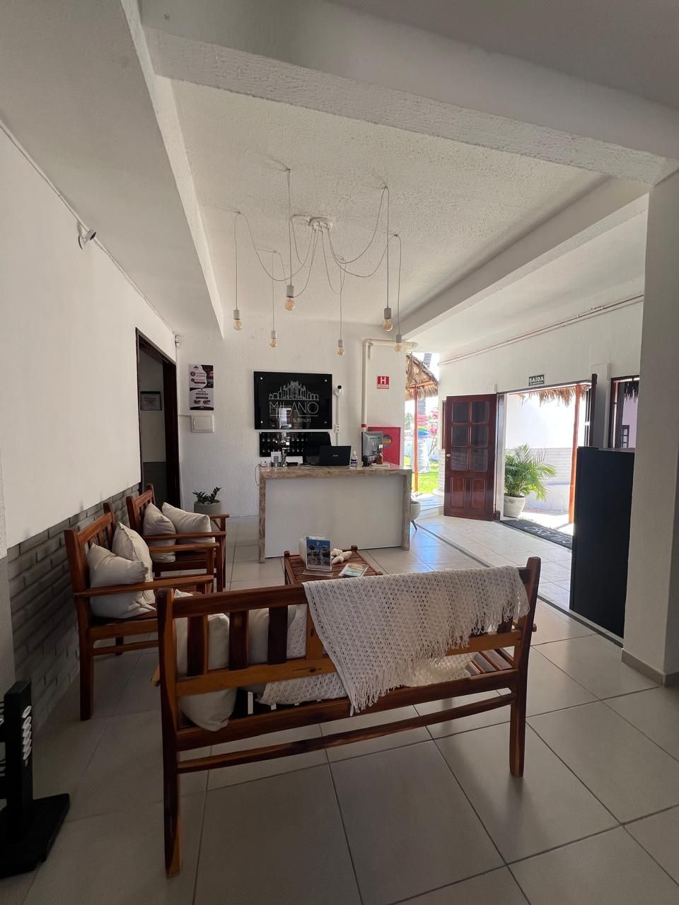 A spacious living area with a sofa, a coffee table, and a television. There is a kitchen area with a refrigerator and a counter.