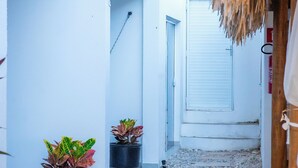 A narrow stone pathway flanked by potted plants and a white building with a closed door. - Milano Hotel Pousada Canoa Quebrada (Aracati)