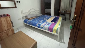 Ein Schlafzimmer mit einem Bett, einer hölzernen Bank, einem Schreibtisch und einem Stuhl.