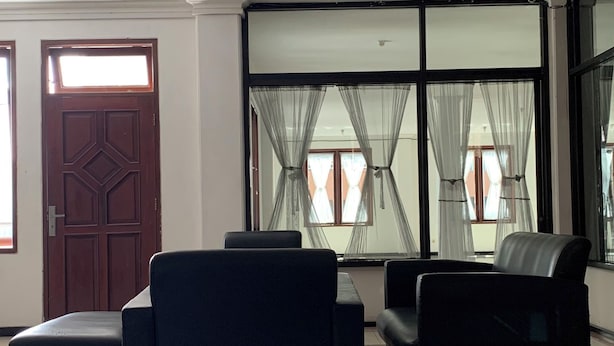 Eine geräumige Lobby mit hoher Decke, einer Holztür und großen Fenstern mit durchsichtigen Vorhängen.