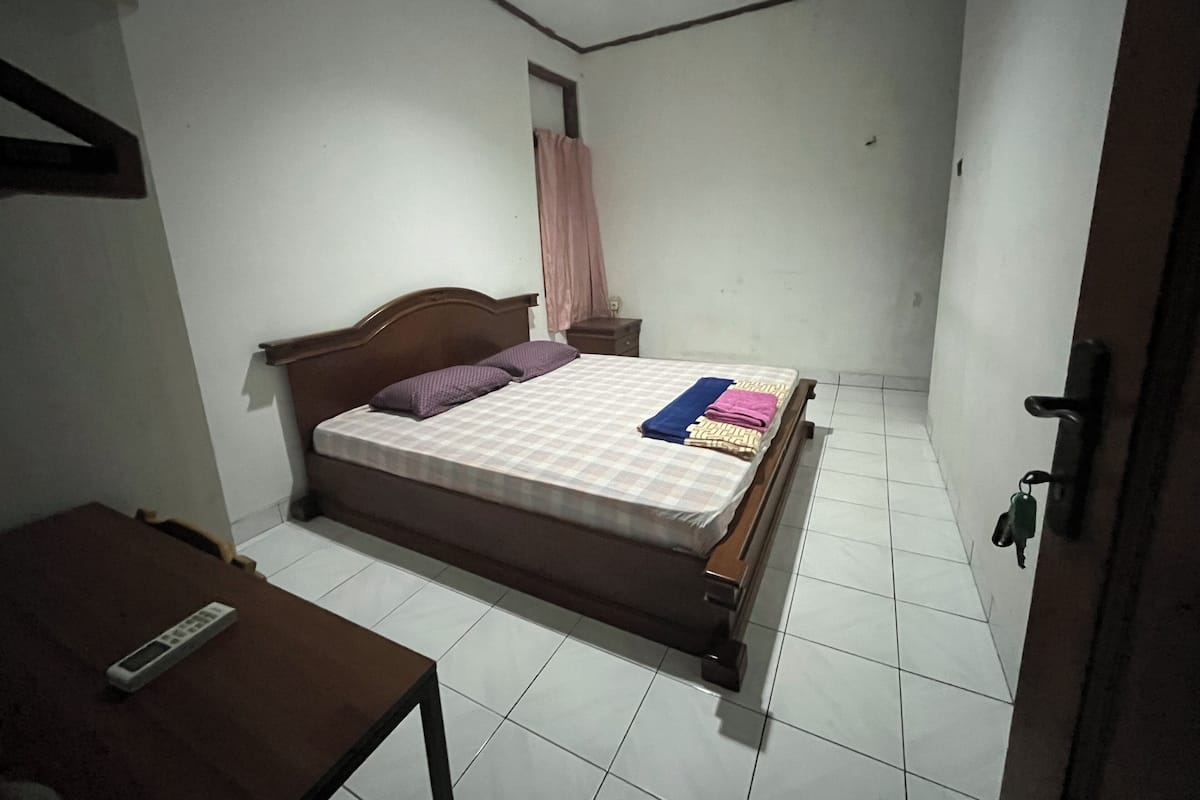 Une chambre à coucher avec un lit, une table de chevet, une table et une porte.