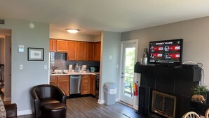 Ein modernes Wohnzimmer mit Kamin, Fernseher und Essbereich.