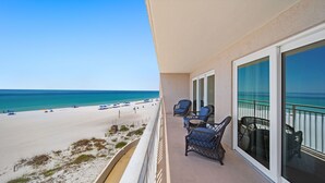 A balcony with wicker chairs, a view of a beach, and a clear sky. - D302 Relax on the Gulf – Beachfront 2BR/2BA with Incredible Views (Panama City Beach)