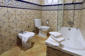 Un baño con inodoro, lavamanos y bañera, todo con diseños de azulejos a juego.