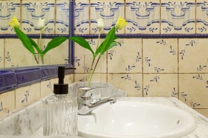 Ein Badezimmer mit einem weißen Waschbecken, einem Spiegel und einer dekorativen Fliesenrückwand.
