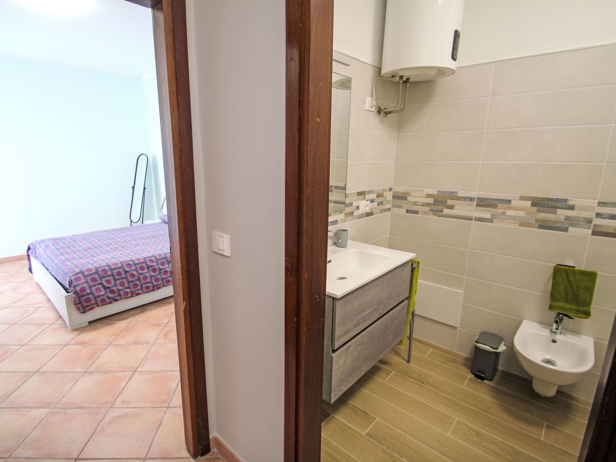 A bedroom with a bed and a bathroom with a sink and bidet.