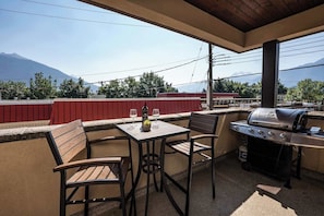 Une terrasse extérieure équipée d’un barbecue, de sièges et d’une table avec des verres à vin.