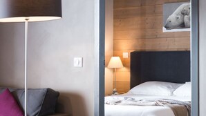 Een hotelkamer met een bed, nachtkastje, lamp en een aan de muur hangend schilderij.