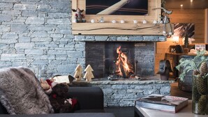 Een gezellige woonkamer met een stenen muur, een open haard en een televisie erboven.