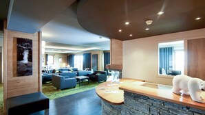 Een moderne hotellobby met een stenen balie, een zithoek en een groot raam.
