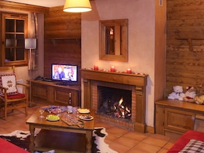 A cozy living room with a fireplace, a television, and a dining table set with food and drinks.