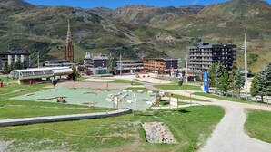 Estância de esqui com edifícios, teleférico e montanhas ao fundo.