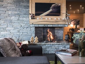 Een gezellige woonkamer met een stenen muur, een open haard en een televisie erboven.