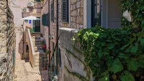 A narrow stone pathway flanked by buildings with green shutters and ivy. - Hedera Estate, Hedera Studio 7 (Dubrovnik)