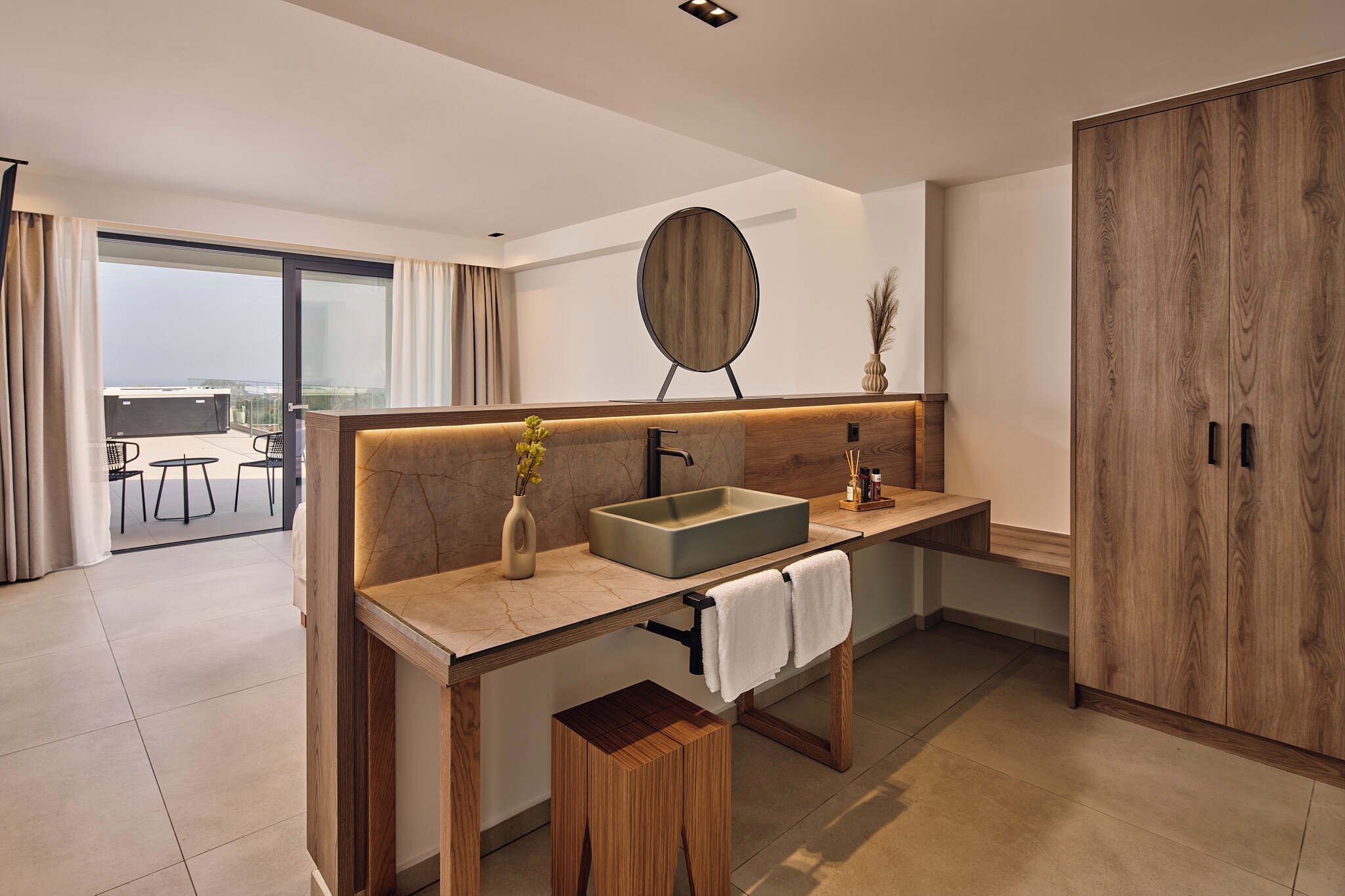 A modern bathroom with a large mirror, a sink, and a wooden vanity.