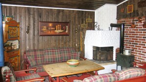 Una habitación acogedora con un sofá de cuadros, una mesa de madera y una chimenea.