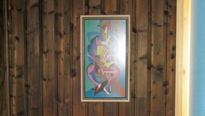 Un baño con paneles de madera, un cuadro abstracto enmarcado y dos inodoros negros.