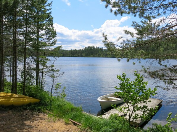 A calm lake surrounded by trees, a dock with a boat, and a yellow kayak. - Telemarkshytta by Interhome (Treungen)
