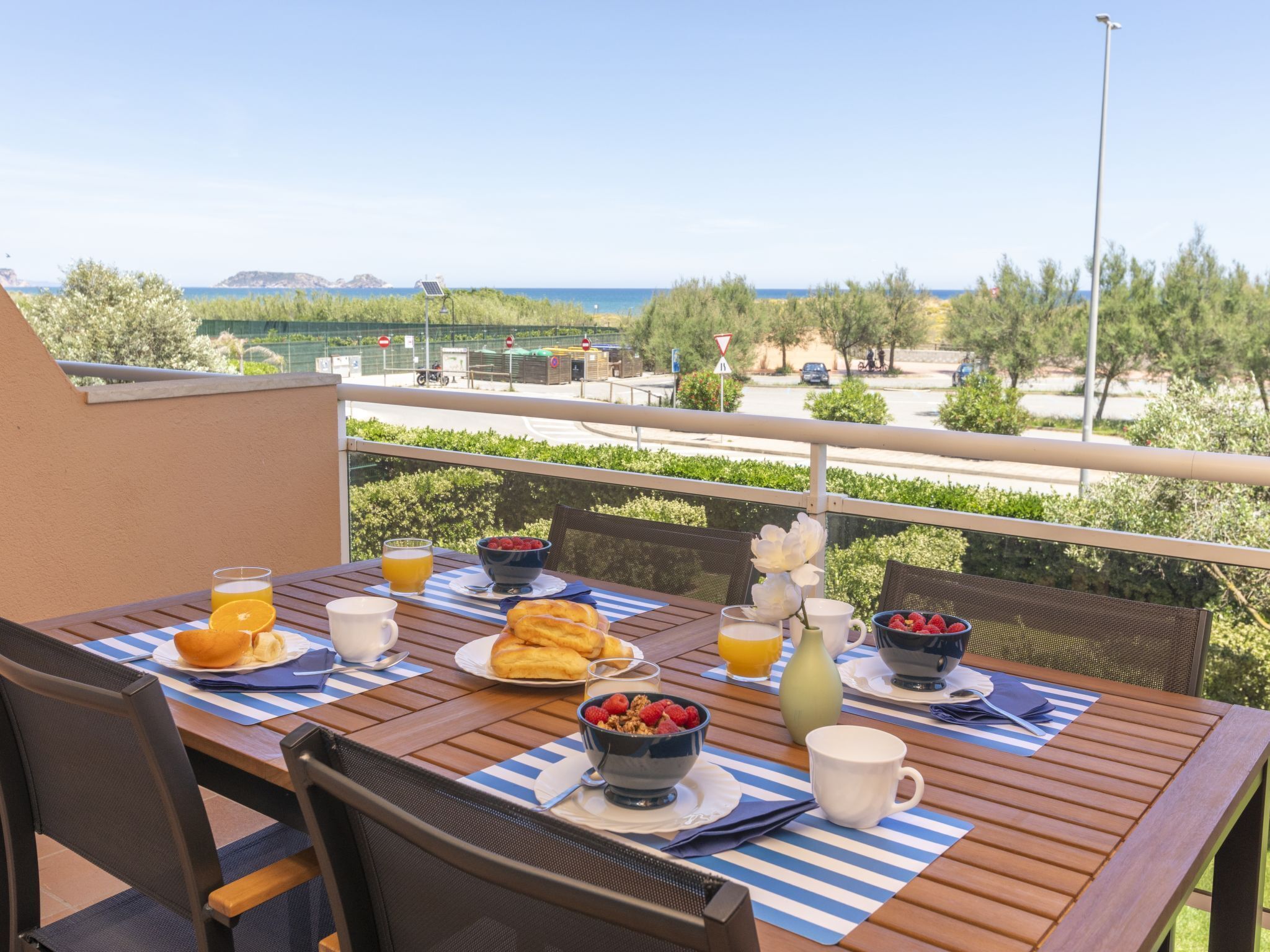 A balcony with a table set for breakfast, overlooking a scenic view.