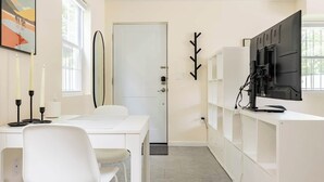Una cocina moderna con muebles blancos, una mesa de comedor con sillas, un ventanal grande y una puerta.