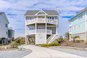 A multi-story residential building with a balcony, a covered entrance, and a clear sky.